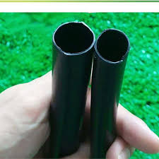 صورة تبرز خرطوم ري أسود سادة في حديقة، مع التركيز على قدرته على التكيف مع مختلف الاسطح